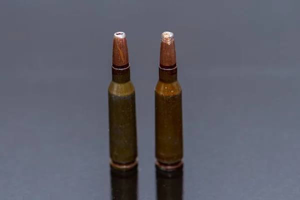 Two automatic cartridges with bullets with an offset center, caliber 5.45 are on a dark background. Concept:prohibited expansive bullets, military ammunition.