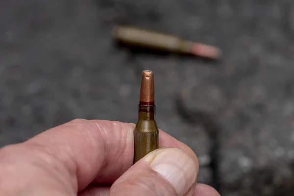 Een Expansieve Kogel Zijn Handen Tegen Achtergrond Van Gebarsten Asfalt — Stockfoto