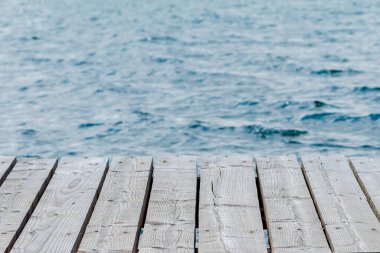 Gölün arka planına karşı suyun üzerinde tahtalardan yapılmış ahşap bir platform. Konsept: Turizm ve seyahat, açık hava eğlencesi.