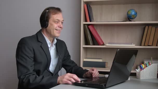Ένας 45Χρονος Κάθεται Στο Γραφείο Ένα Λάπτοπ Ακουστικά Επικοινωνώντας Μέσω — Αρχείο Βίντεο