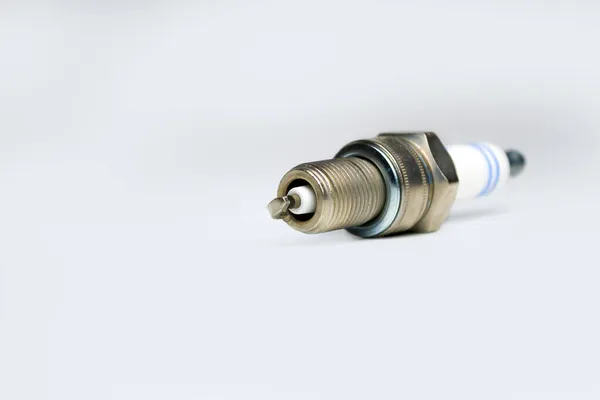 Auto service. New car spark plug as spare part of auto transportation on gray background. — Stock Photo, Image