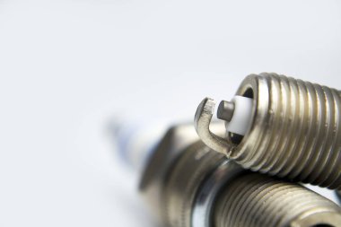 Yaratıcı soyut araba onarım hizmeti ve otomotiv sektörü iş konsepti: beyaz arka planda izole edilmiş metal bujilerin makro görünümü ve seçici odak etkisi