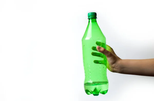 Tangan kekanak-kanakan memegang botol hijau pada latar belakang putih. — Stok Foto
