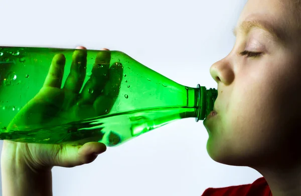 Anak itu minum air dari botol dengan latar belakang putih. — Stok Foto