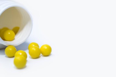 Beyaz arka planda kapsül şeklinde tablet şişesi