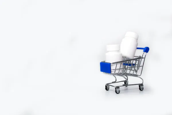 Compras de medicamentos, custos de saúde e prescrição conceito de medicação com carrinho de compras ou carrinho cheio de pílulas isoladas em fundo azul com espaço de cópia — Fotografia de Stock