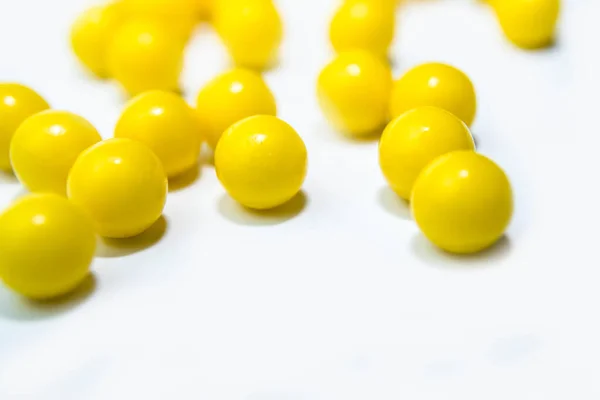 Amarelo redondo pílulas vitaminas bada na mesa branca de perto — Fotografia de Stock