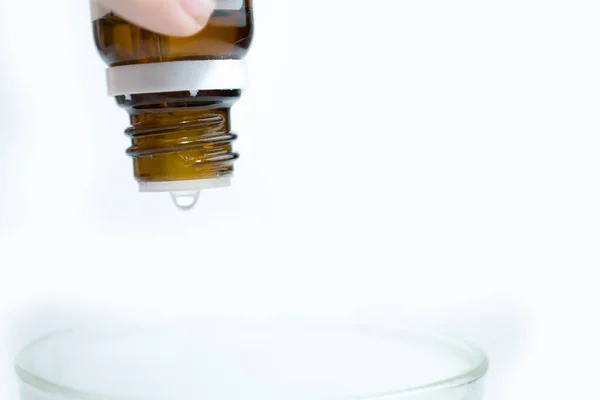 En flaska läkemedel droppas i ett glas vatten för att komma in. — Stockfoto