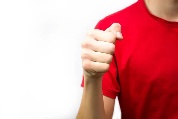 Killen till den röda t-shirten knöt näven mot en vit bakgrund, aggression redo att slåss. — Stockfoto