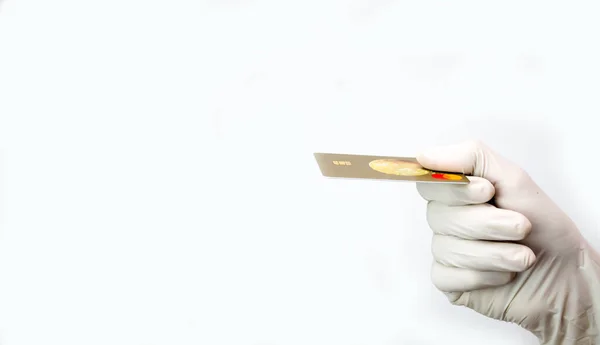 Uma mão em uma luva protetora branca segura o cartão de crédito em um fundo branco. — Fotografia de Stock