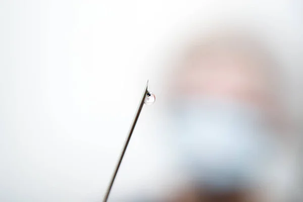 The needle from the syringe with a drop on the end in the background blurred patient. — Fotografia de Stock