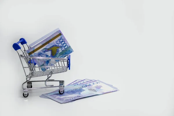 Tenge Kazakhstani dinheiro em um carrinho em um fundo branco. — Fotografia de Stock