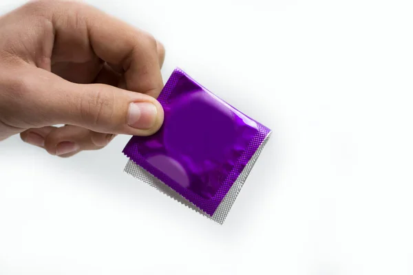 Hand pack blå kondom på en vit bakgrund, koncept skydd mot aids. — Stockfoto