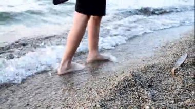 Bir çocuk sahilde yalınayak yürüyor, su dalgalarında, ayak masajı rahatlığında..