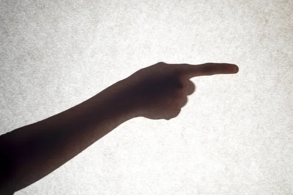 Skuggan av en hand med ett utsträckt finger pekar åt sidan. — Stockfoto