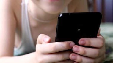 Çocuk yatakta yatıyor ve bir akıllı telefondan cevap veriyor..