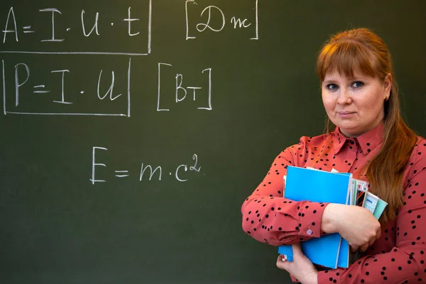 A physics teacher stands near the blackboard where formulas for physics are written. — Stock Photo, Image