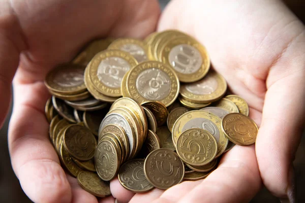 Frauenhände halten ein Bündel Münzen mit einem Nennwert von 100 Tenge, dem Existenzminimum. Stockbild