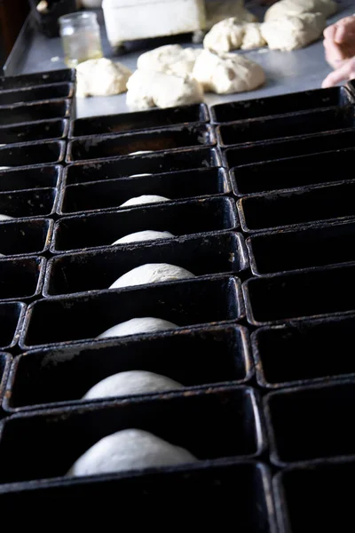 Colocar la masa en los moldes para el pan futuro. — Foto de Stock