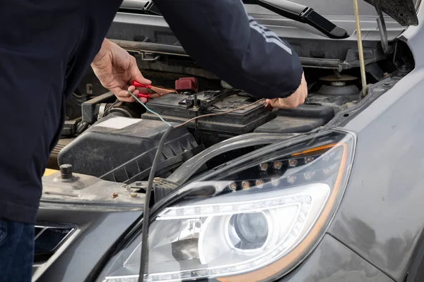 Automechaniker nutzt Batterieüberbrückungskabel, um tote Batterie aufzuladen Stockfoto