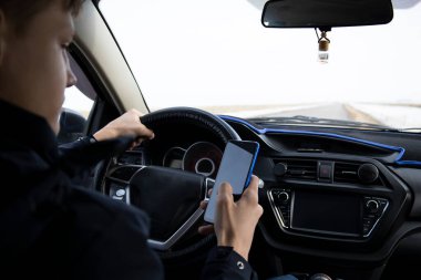 Genç bir adam araba kullanırken telefonla konuşuyor..