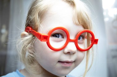 Bebek gözlüklü üç yaşında bir kız doktorculuk oynuyor..