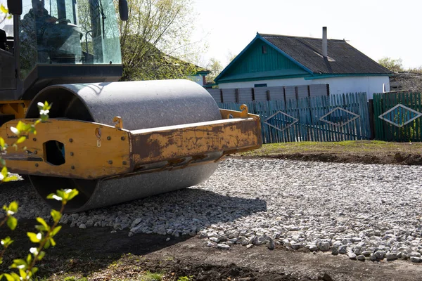 The roller rolls the gravel preparing the soil for the road. Rural road repairs in Kazakhstan. — Stock Photo, Image