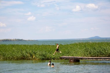 Boy jumping in lake water at summer holiday. High quality photo