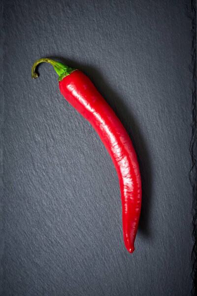 Red chilli pepper on a dark stone background. Top view.