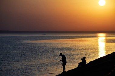 Denizde güzel bir yaz günbatımı. Kıyıdaki insanların silueti. Deniz manzarası.