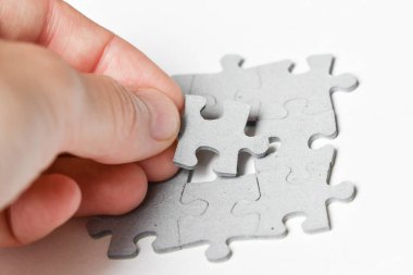 Beyaz arkaplana sığdırmak için yapbozun son parçasını ekleyen kişinin fotoğrafı