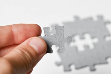 Beyaz arkaplana sığdırmak için yapbozun son parçasını ekleyen kişinin fotoğrafı