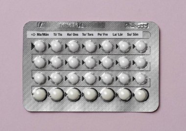 Pembe arka planda doğum kontrol haplarının tam tablosu