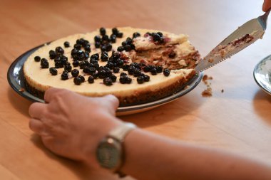 Üzerinde yaban mersini olan bir dilim pasta kesen bir kadın.