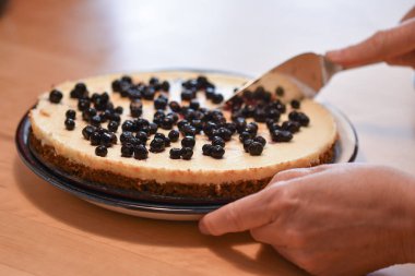Üzerinde yaban mersini olan bir dilim pasta kesen bir kadın.