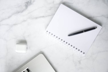 Beyaz mermer arka planda dizüstü bilgisayar ve defter