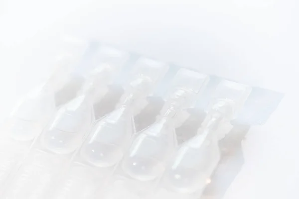 Photo of containers for eye drops on white background