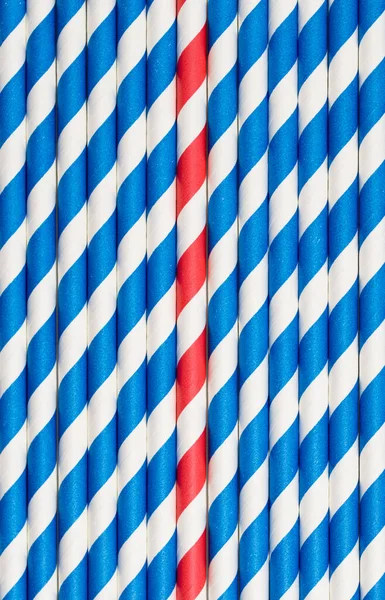 Full frame photo of blue and white straws from above, one red straw is different