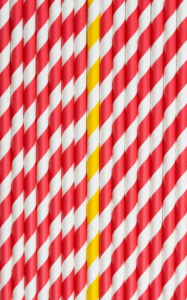 Full frame photo of red and white straws from above, one yellow straw is different