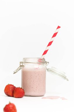 Çilekli milkshake 'in stüdyo fotoğrafı ya da beyaz arka planda kırmızı pipetli smoothie.