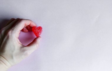 Kırmızı jöleli şekerin fotoğrafı. Beyaz arka plandaki kadının elinde.