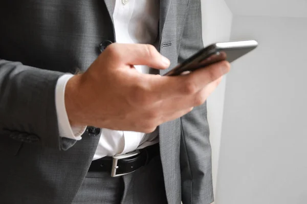 Midsection of businessman holding a mobile phone for communicating