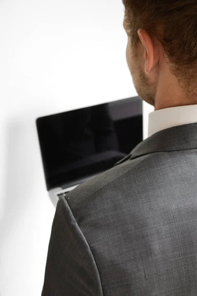 Businessman behind a laptop computer against white background