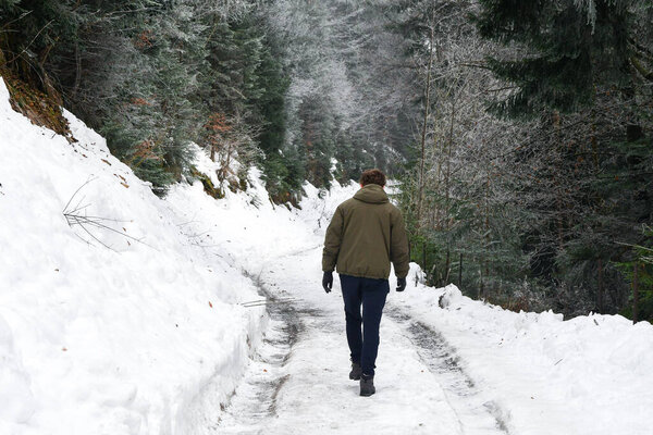 A man from behind walking in mountains during snow and winter season