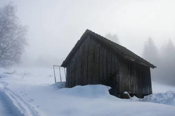 A small mountain cottage or house during fog and snow in winter