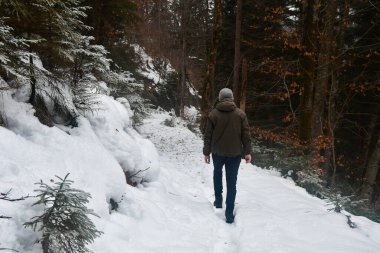 Kar ve kış mevsiminde dağlarda yürüyen bir adam.