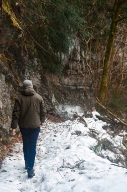 Kar ve kış mevsiminde dağlarda yürüyen bir adam.