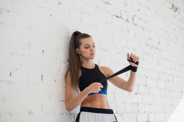 Antrenmanın başında, güzel bir kickboksçu kız bandaj sararak ellerini hazırlar.