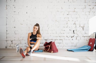 Kadın dövüşçü, egzersizden sonra susuz kalıp biberondan izotonik içecek içiyor. Genç bir kadın bir boks stüdyosunda yoğun bir eğitimden sonra dinleniyor..