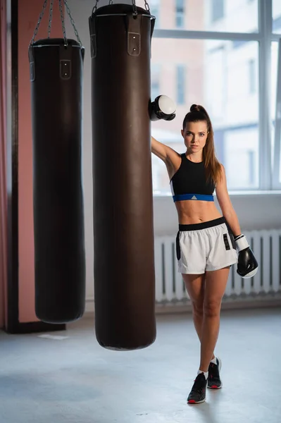 Sesión de fotos para un joven atleta en el interior de un gimnasio de boxeo con guantes y bolsas — Foto de Stock